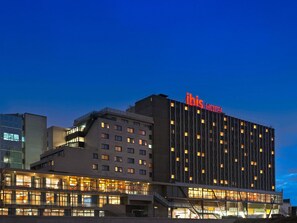Un hotel de diseño moderno, con varios pisos y un llamativo letrero de 'ibis hotel'.