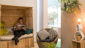 A cozy room with a wooden bench, a wicker chair, and a potted plant. - ibis Paris 17 Clichy-Batignolles (Paris)