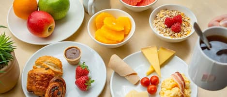 Una mesa de desayuno con platos de comida, una taza de café y un vaso de jugo de naranja.