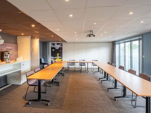 A conference room with a long table, chairs, a projector, and a coffee station. - ibis Paris 17 Clichy-Batignolles (Paris)