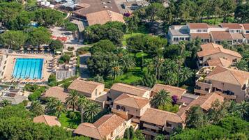 Luchtbeeld van een resort met meerdere villa's, een zwembad en weelderige begroeiing.