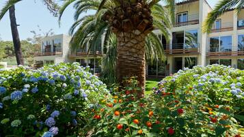 Un hotel de diseño moderno, con una palmera en el centro y un jardín lleno de flores.