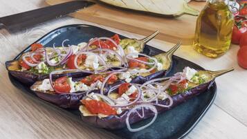 A plate of stuffed eggplants with tomatoes, onions, and feta cheese.