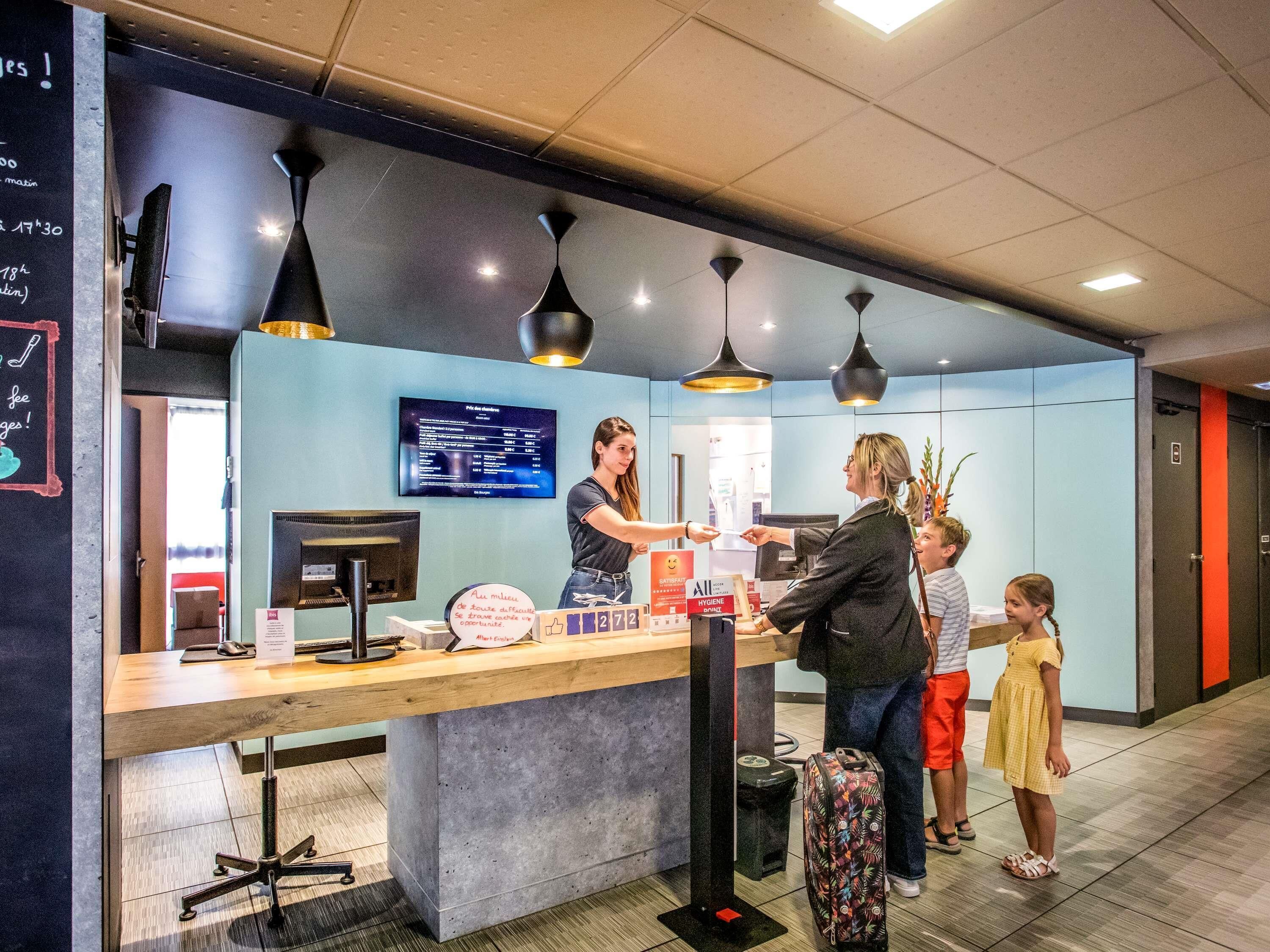 A reception desk with a computer monitor, a menu board, and a sign indicating hygiene standards.