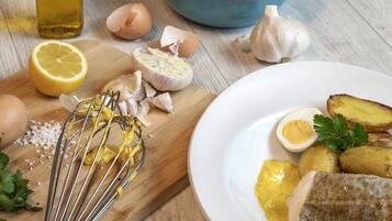 Eine Küchenarbeitsplatte mit Zutaten und Utensilien, darunter Eier, Knoblauch, Zitrone und ein Schneebesen.