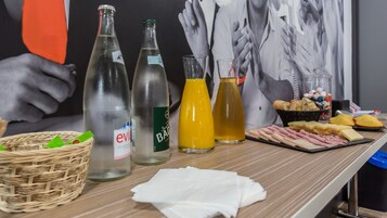 Uma mesa com garrafas, uma cesta e uma tábua de queijos.
