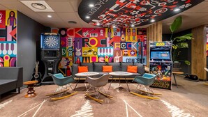 A vibrant room with a dartboard, a guitar, a Star Wars arcade game, and a colorful wall mural. - B&B Hotel Boulogne Sur Mer Centre Les Ports (Boulogne-sur-Mer)