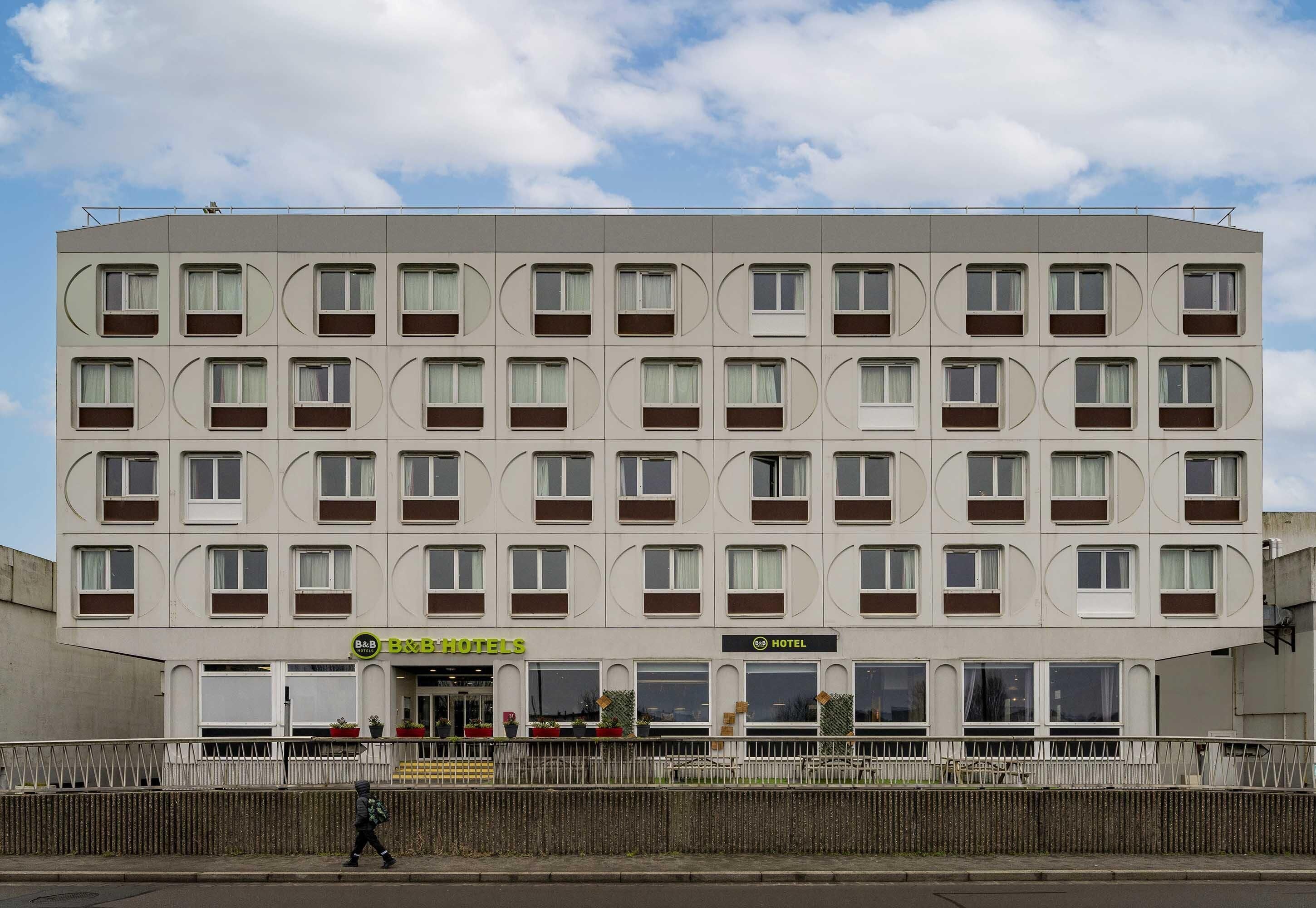 Un hôtel à plusieurs étages, doté d’une façade symétrique, de grandes fenêtres et d’un toit plat.