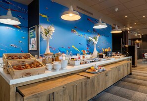 A buffet counter with wooden crates of pastries, a variety of food items, and decorative vases. - B&B Hotel Boulogne Sur Mer Centre Les Ports (Boulogne-sur-Mer)