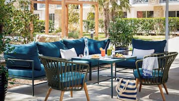 Un espacio al aire libre con sofás, sillas y una mesa dispuesta con comida y bebidas.