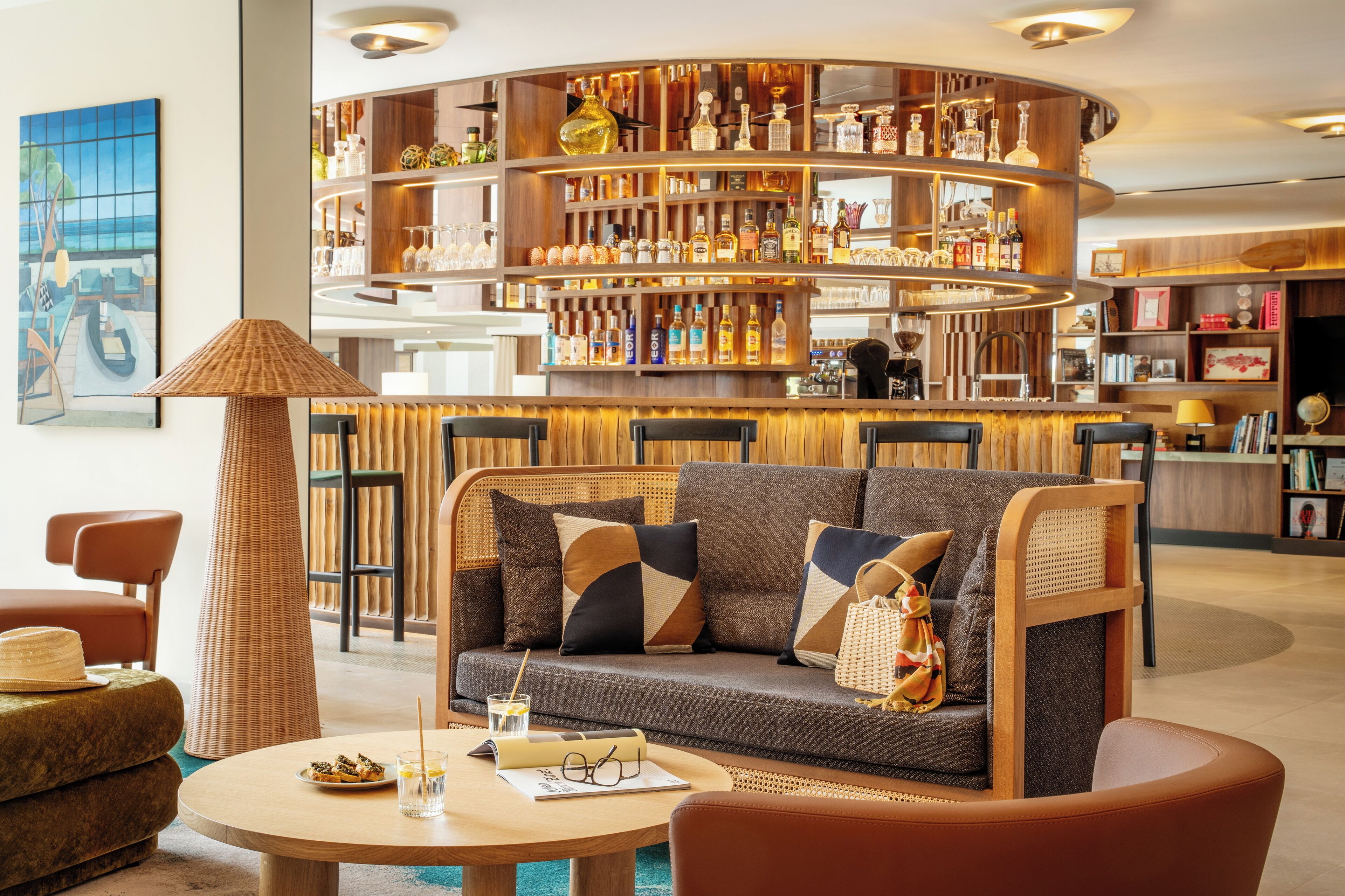 Un área de bar moderna con una estantería curvada que exhibe diferentes botellas y vasos.