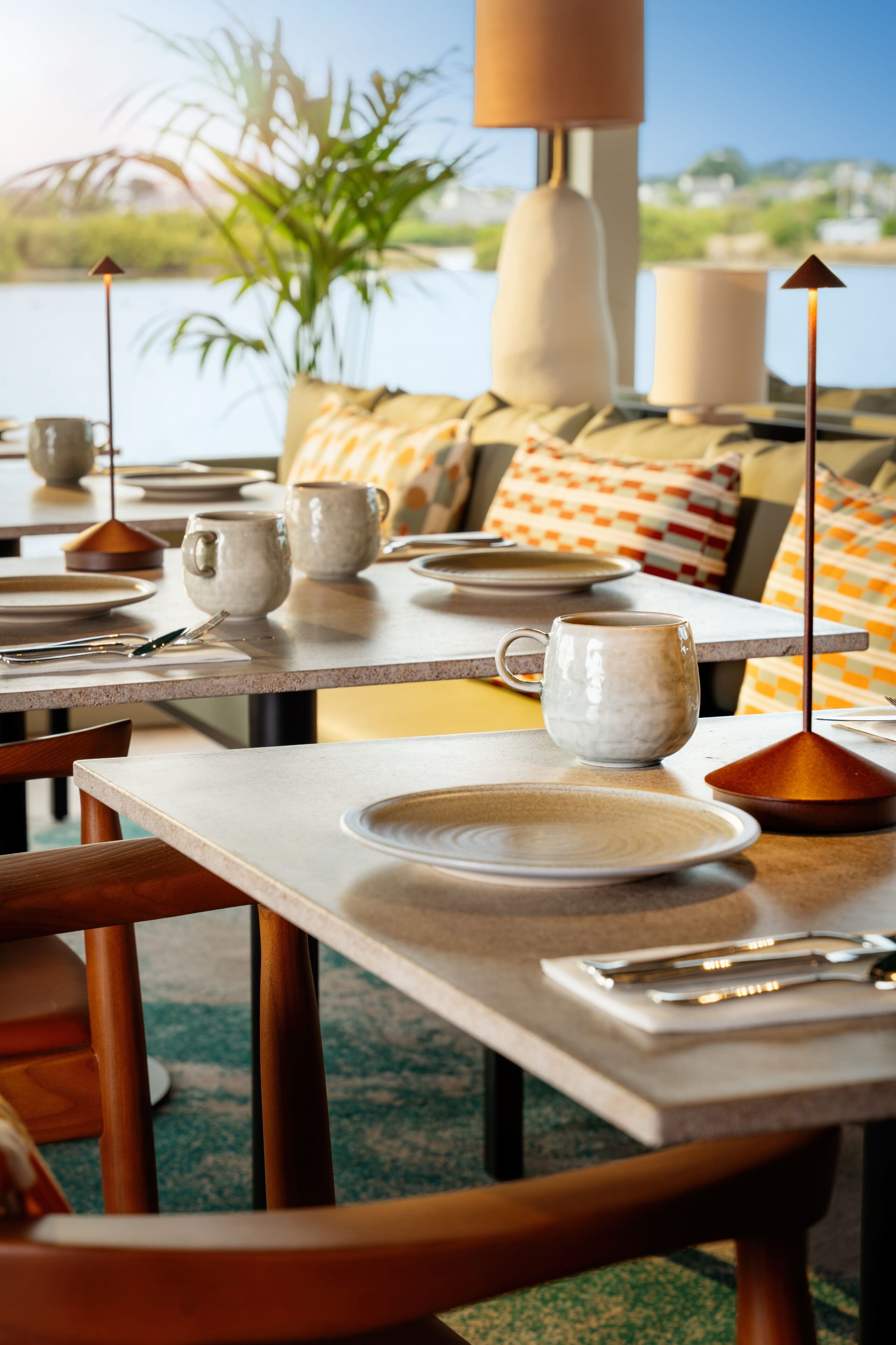 A dining area with tables set for a meal, featuring plates, cups, and cutlery.