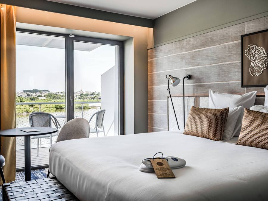 Habitación de hotel con cama, escritorio, silla, mesa y vistas a la ciudad.