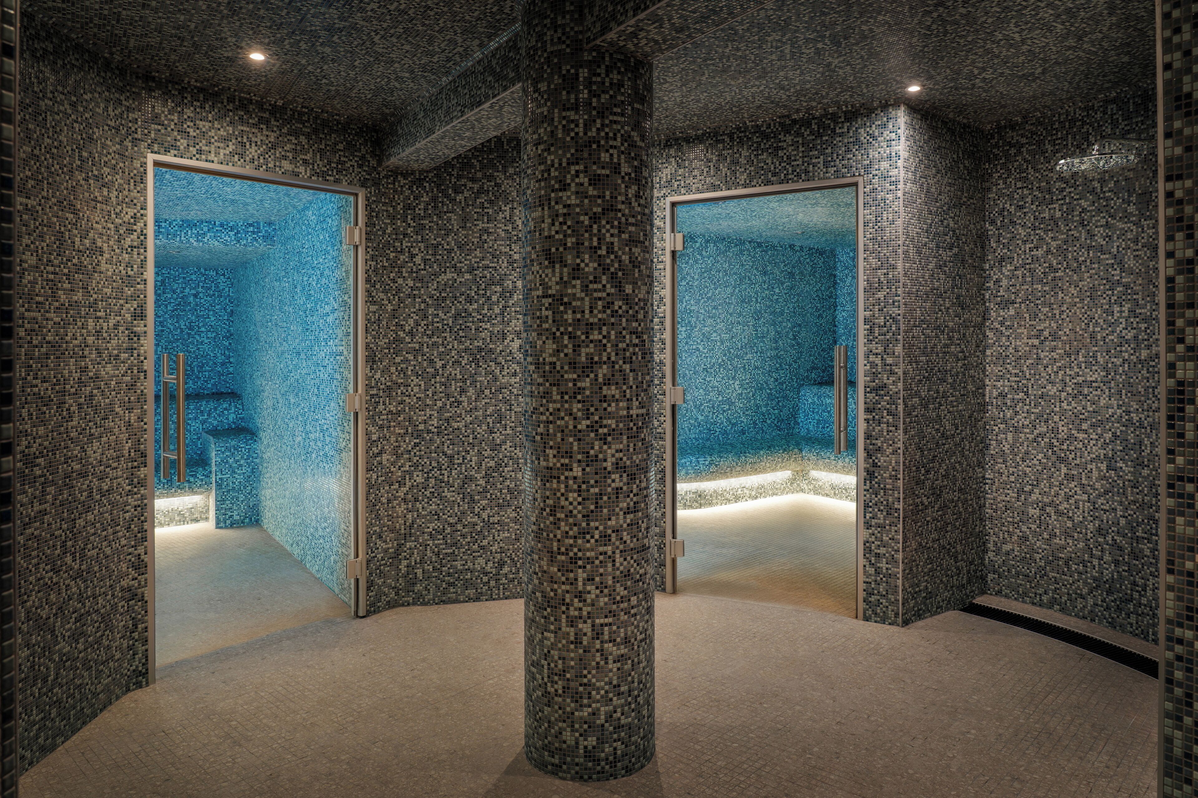 Un espace spa moderne avec des murs recouverts de mosaïques et un pilier central.