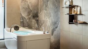 Une salle de bain moderne avec un mur en pierre, une baignoire et des étagères minimalistes ornées d’objets décoratifs.