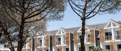 Un hotel de varios pisos con balcones, listones de madera y cielo despejado.