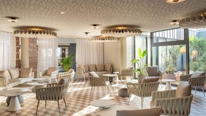 Un salón amplio con suelo a cuadros, asientos cómodos y ventanas grandes que dan vistas al exterior.