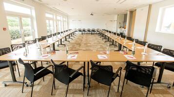 A conference room with long tables, chairs, and water bottles.