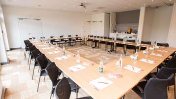 Une salle de conférence équipée de longues tables, de chaises et d’un projecteur.