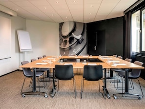 A conference room with a long table, chairs, a whiteboard, and a large abstract wall mural.