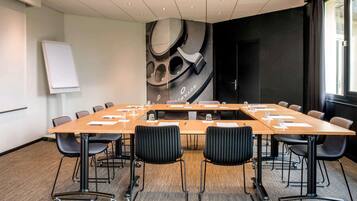 A conference room with a long table, chairs, a whiteboard, and a large abstract wall mural.