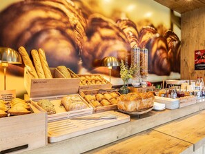 A bakery display with various breads and pastries, a sign indicating gluten-free options, and a backdrop of baked goods. - Ibis Chalons En Champagne (Chalons-en-Champagne)