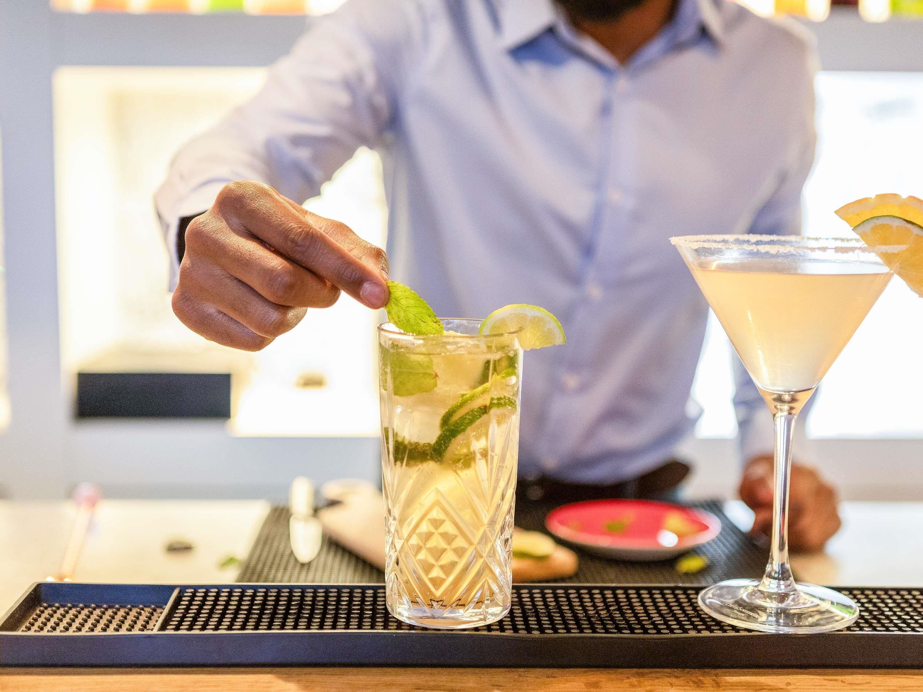 A bartender preparing a drink with a lime garnish.