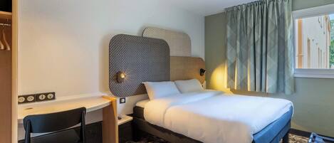 Una habitación de hotel con una cama, un escritorio y una silla.