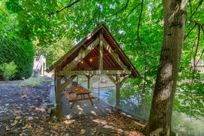 A wooden gazebo with a picnic table, surrounded by trees and a body of water. - B&B HOTEL Chartres Centre Cathédrale (Chartres)