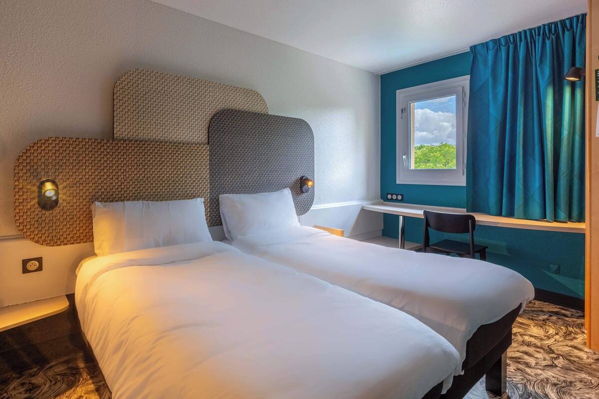 Habitación de hotel con una cama grande, un escritorio y una ventana con cortinas.
