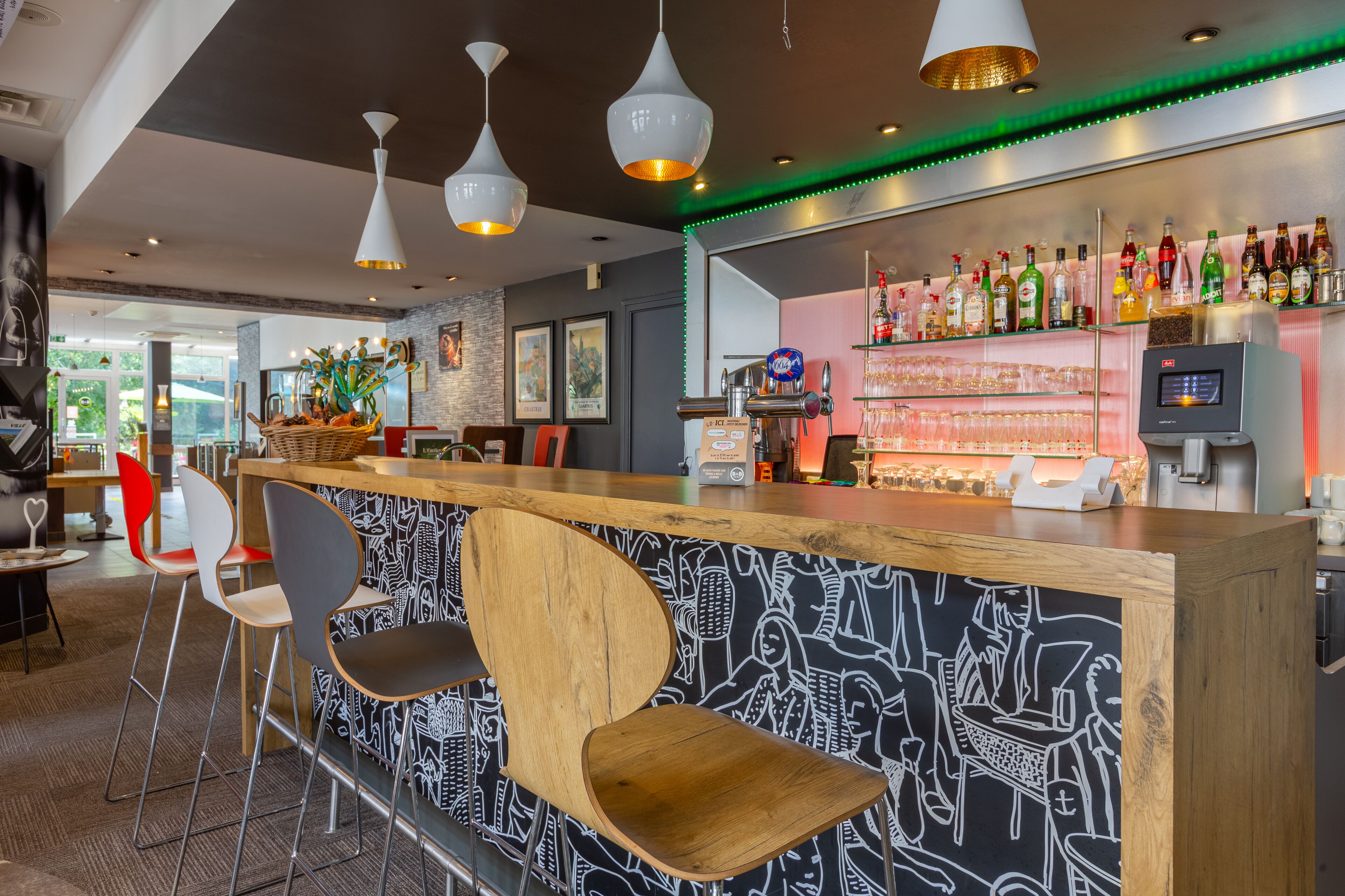 Zona de bar con mostrador de madera, taburetes y una variedad de botellas en estanterías.