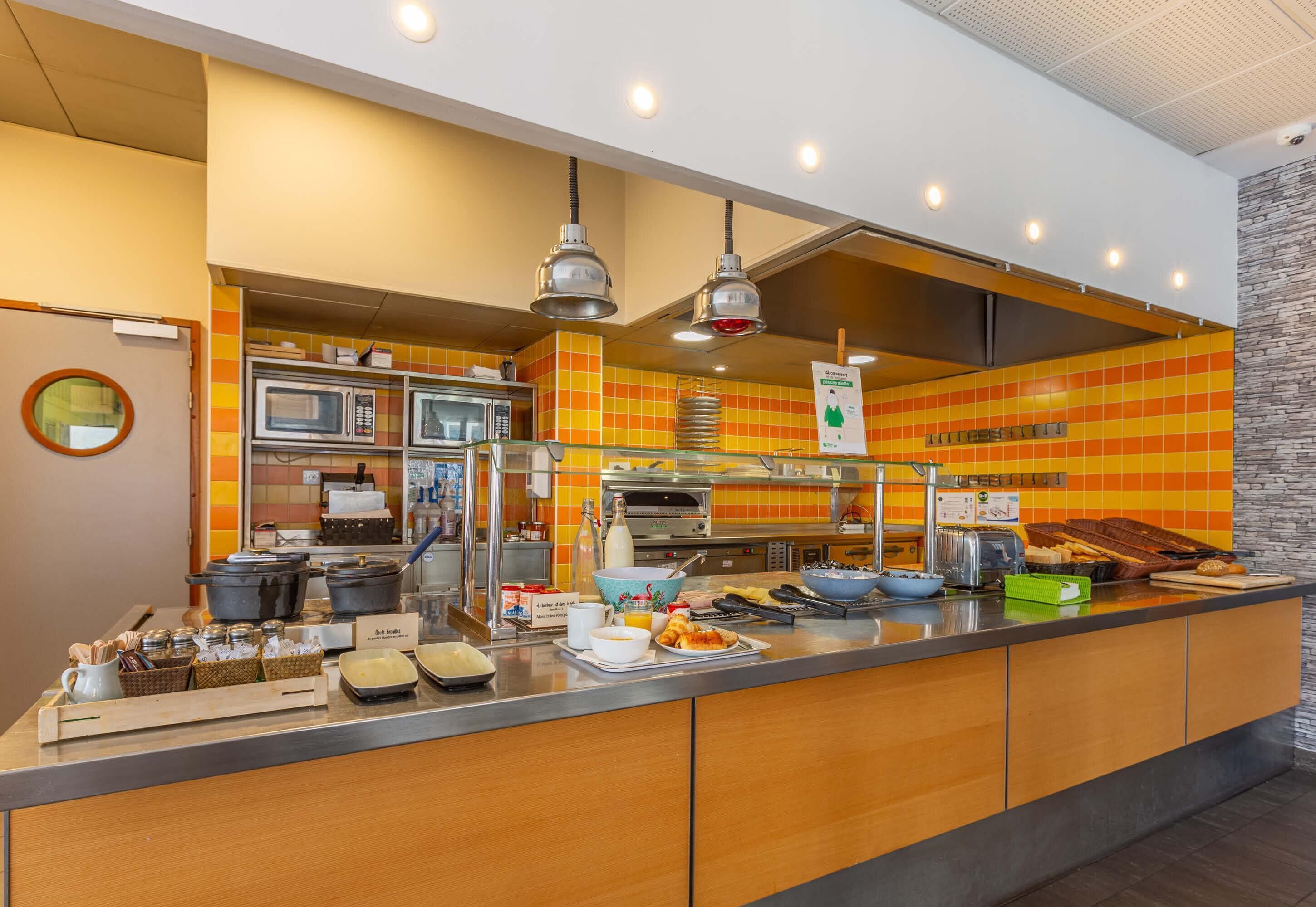 Un espace buffet pour le petit-déjeuner proposant une variété d’aliments, un four à micro-ondes et un coin café.