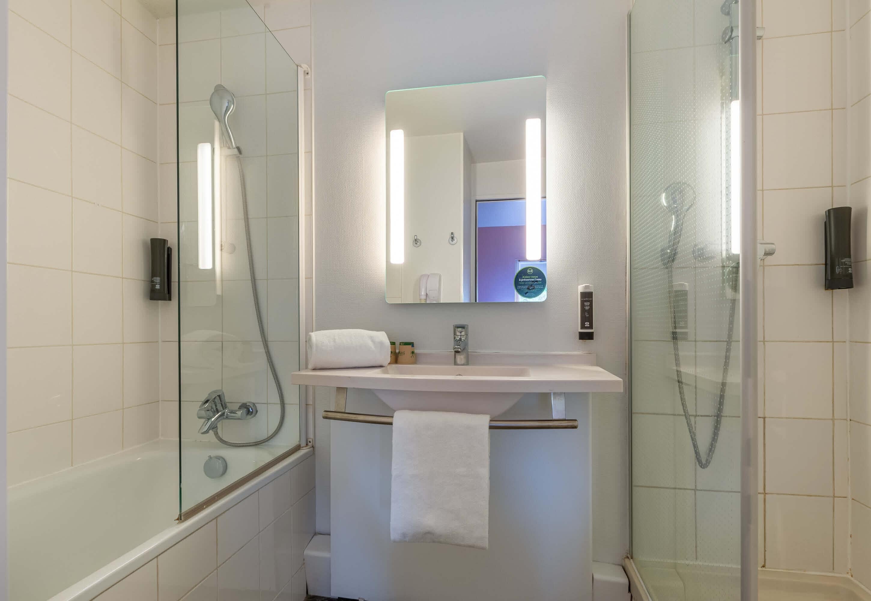 A modern bathroom with a glass-enclosed shower, a white sink, and a mirror above it.