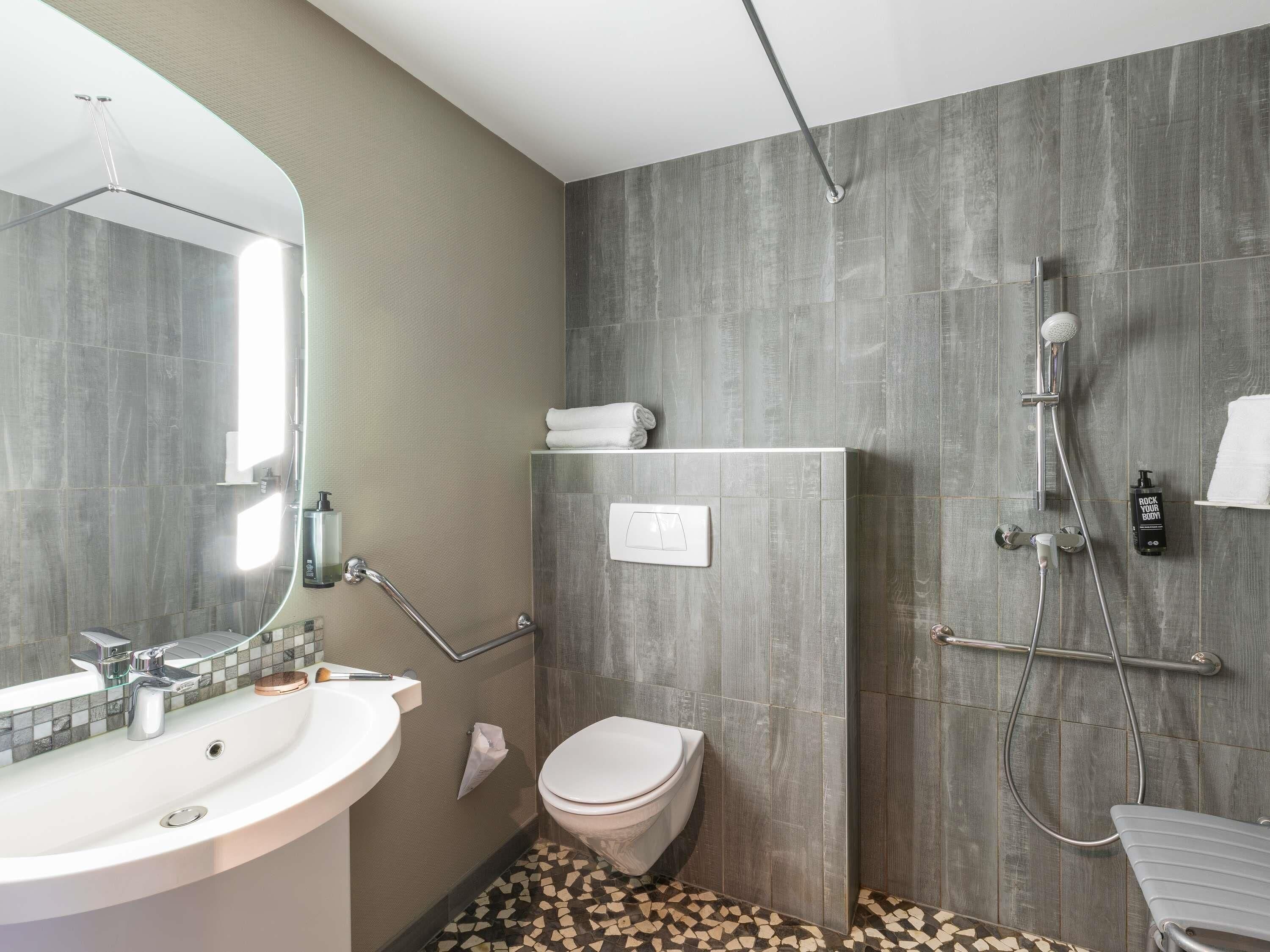Une salle de bain moderne équipée d’un lavabo, de toilettes, d’une douche et d’un porte-serviettes.