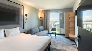 Een moderne hotelkamer met een groot bed, een sofa, een kleine tafel, een stoel en een balkon met uitzicht.