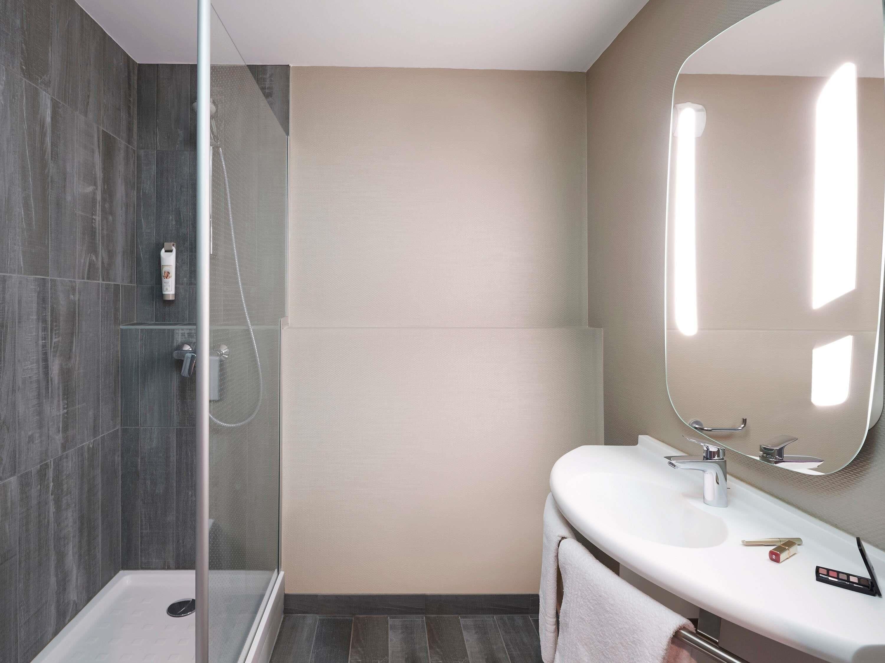 Un baño moderno con cabina de ducha de vidrio, un lavabo blanco y un espejo.