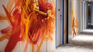 A hallway with doors, one of which has a blue frame and a number sign. - ibis Styles Paris Bercy (Paris)