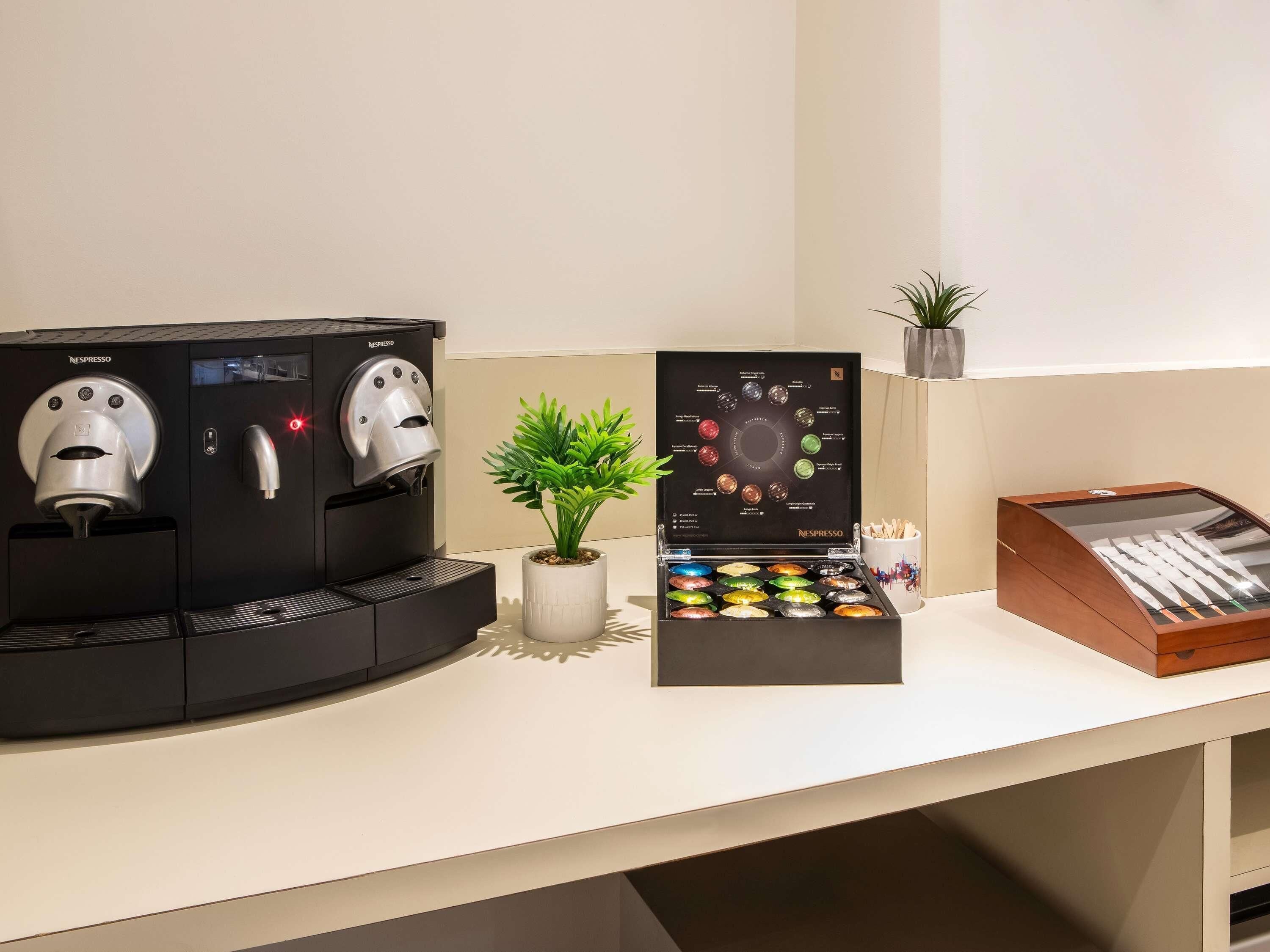 Une machine à café Nespresso, un présentoir de capsules Nespresso et une boîte en bois contenant des grains de café.