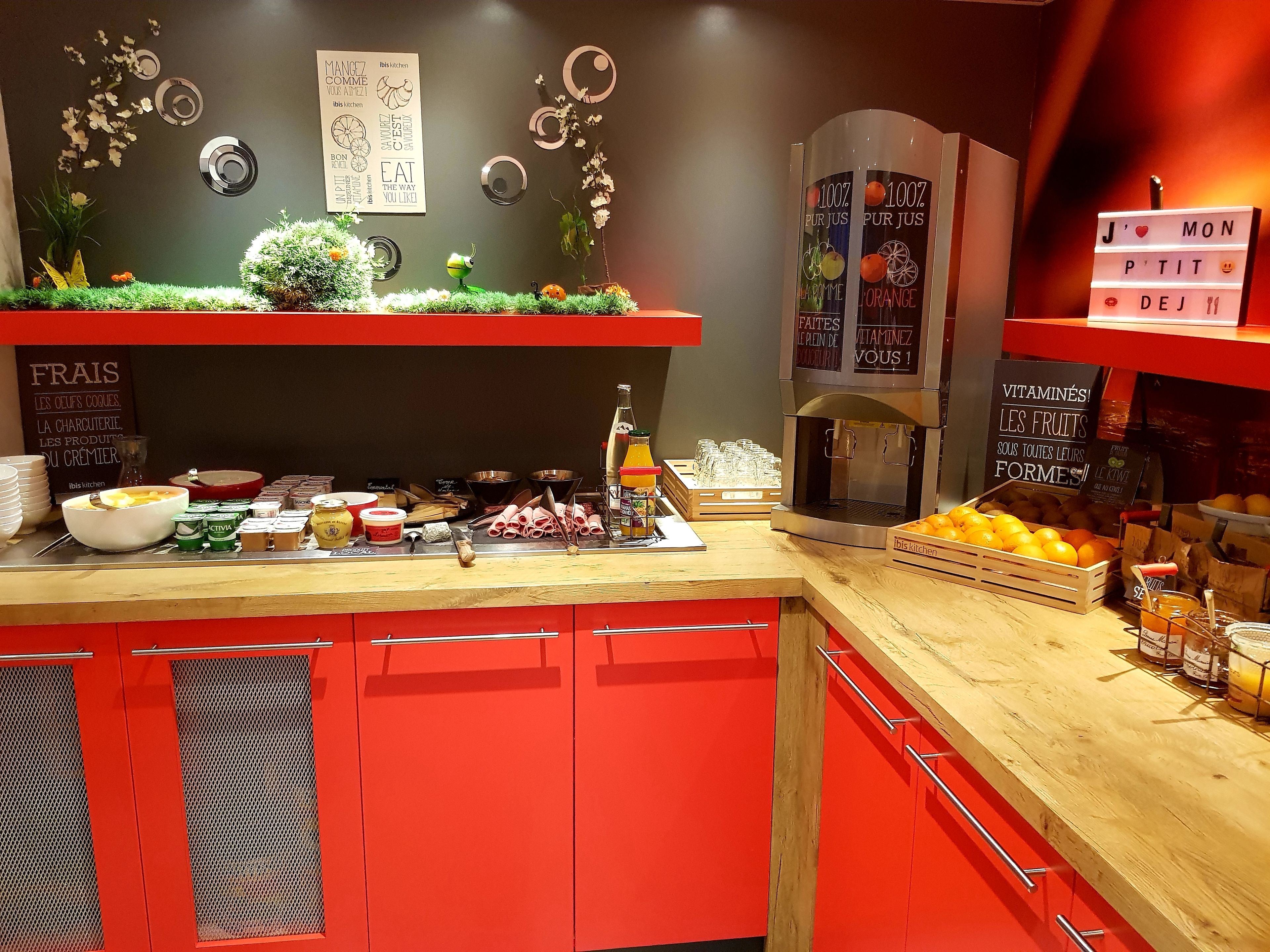 Una barra de desayuno con una máquina de café, una exhibición de frutas y diversos alimentos.