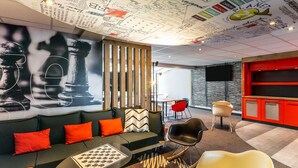 A modern lounge area with a sofa, chairs, a coffee table, and a wall with various writings and drawings. - ibis Chalon-sur-Saone North (Chalon-sur-Saone)
