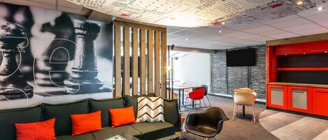 A modern lounge area with a sofa, chairs, a coffee table, and a wall with various writings and drawings.