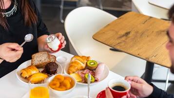 Un desayuno con pan, bollería, fruta y café.