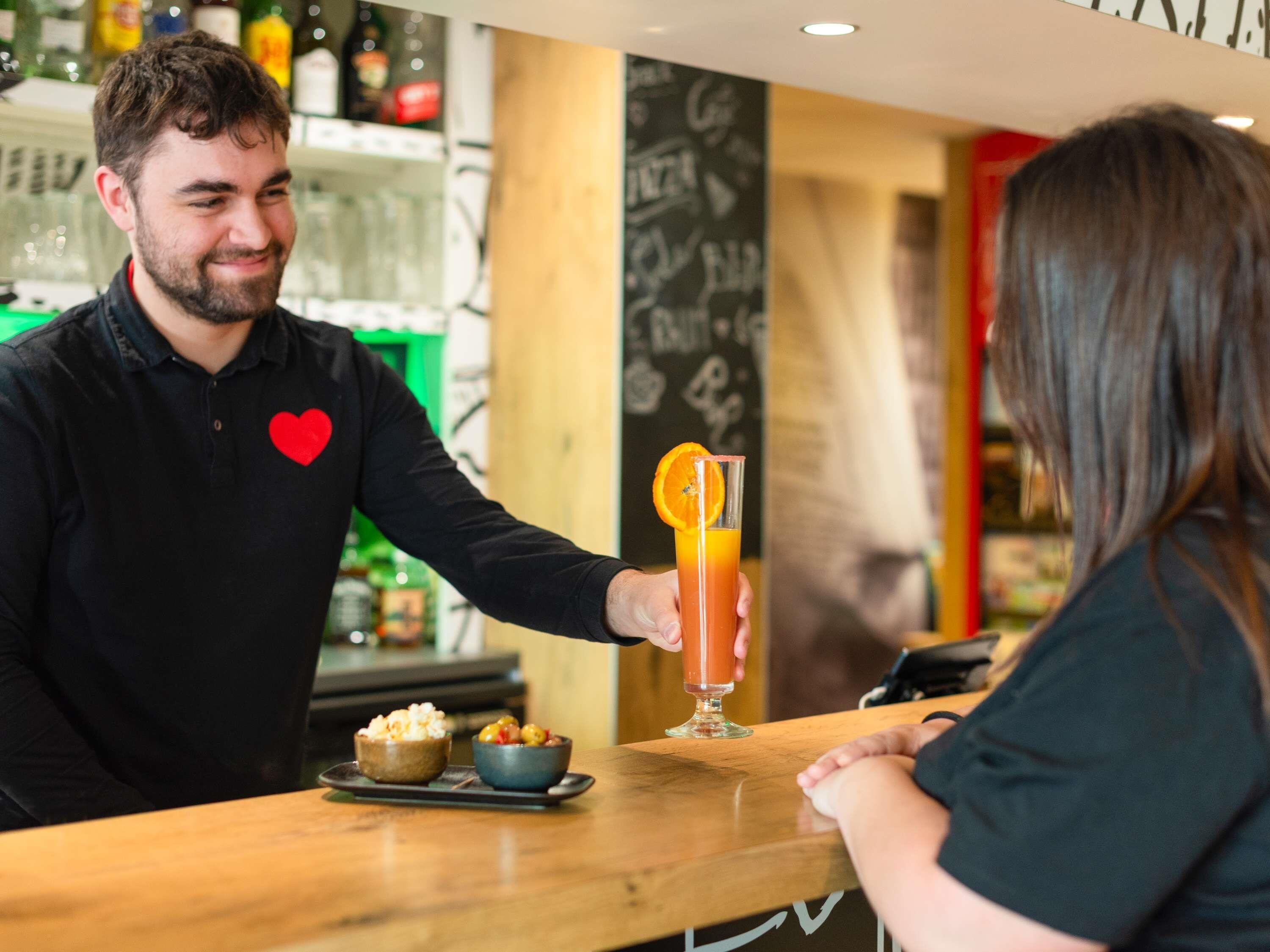 Un bar con un cantinero sirviendo una bebida a un cliente.