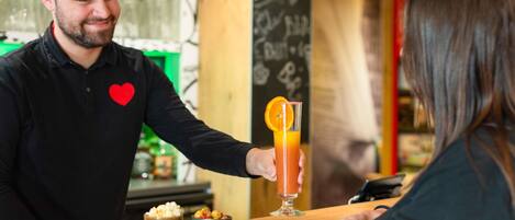 A bar setting with a bartender serving a drink to a customer.