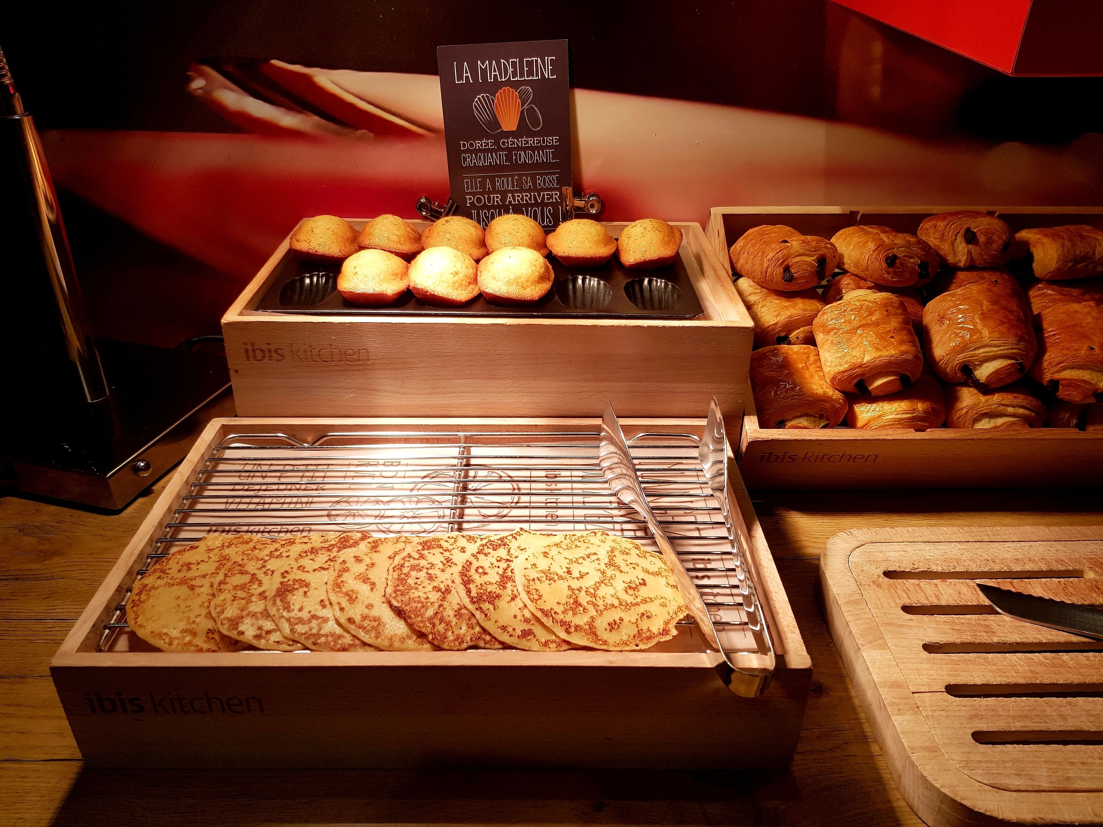 Un bancone di pasticceria con diversi prodotti da forno, tra cui muffin, croissant e dolci.