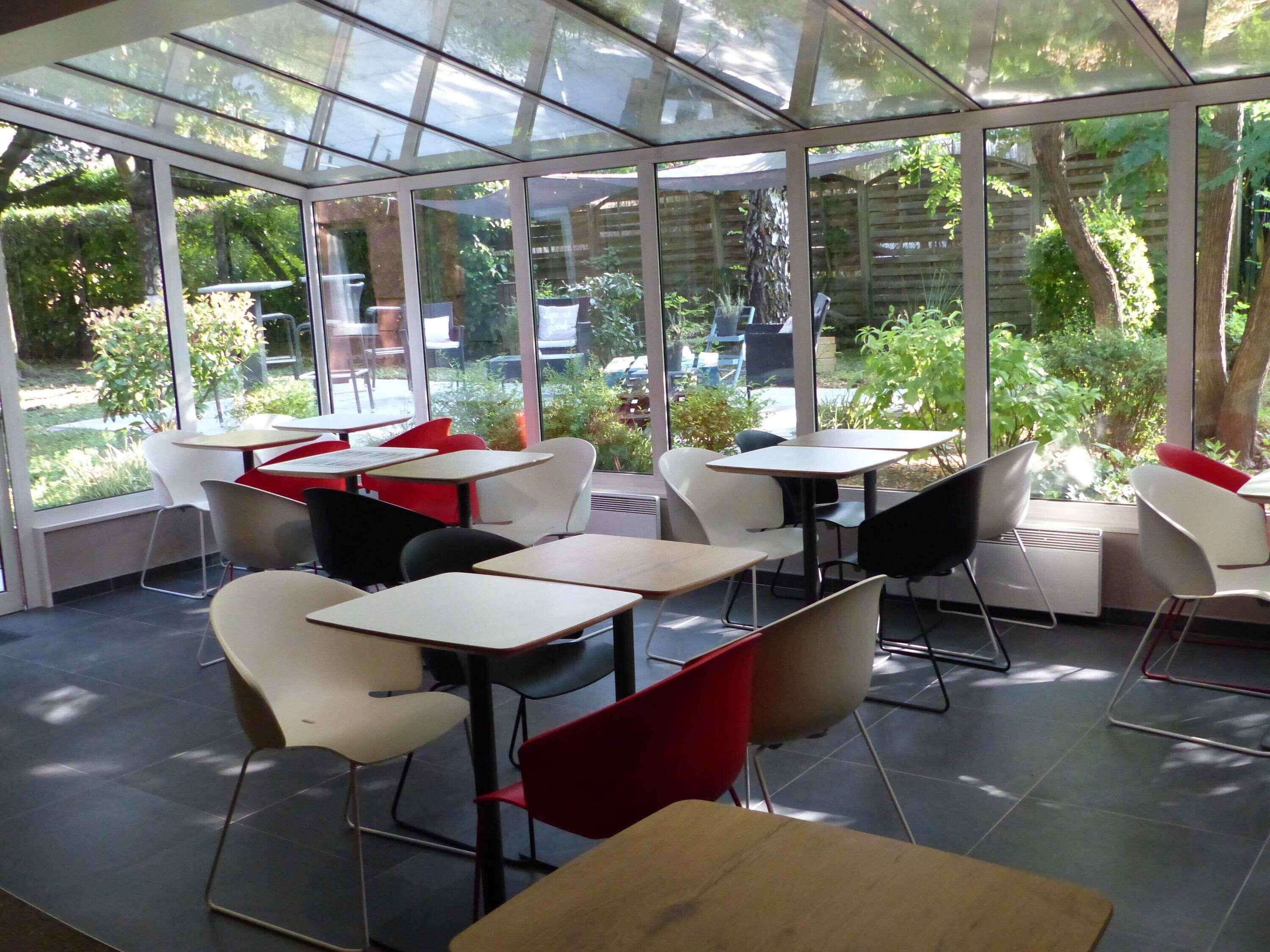 Een modern buitencafé met glazen wanden, tafels en stoelen.