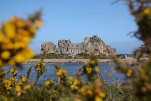 A coastal building with a prominent rock formation, situated by the sea. - ibis Saint Brieuc Yffiniac (Yffiniac)