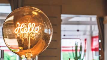 A glowing 'Hello' sign sits atop a wooden base, surrounded by a spacious interior with large windows.