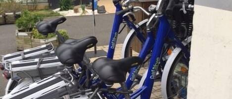Eine Reihe blauer Fahrräder sind vor einem Gebäude abgestellt, an dem ein Schild mit der Aufschrift "ibis" hängt.