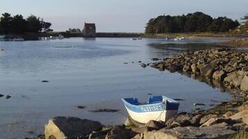 A calm body of water with a small boat on the shore, surrounded by rocks and trees.
